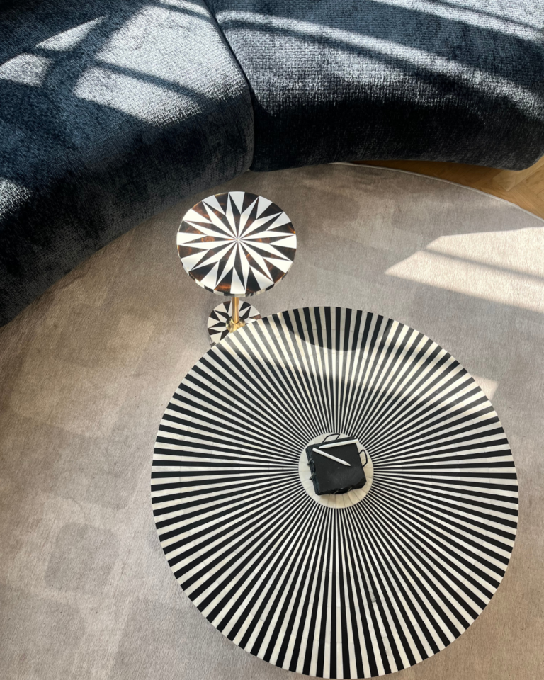 Detailaufnahme einer Couch inklusive Teppich und Couchtische in hellen Farben